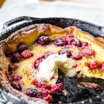 german pancakes with berries in cast iron skillet