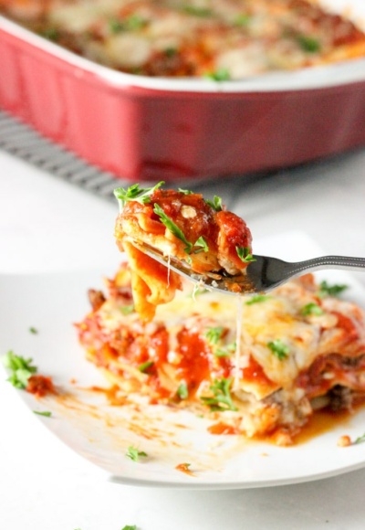 classic lasagna on plate with fork holding bite
