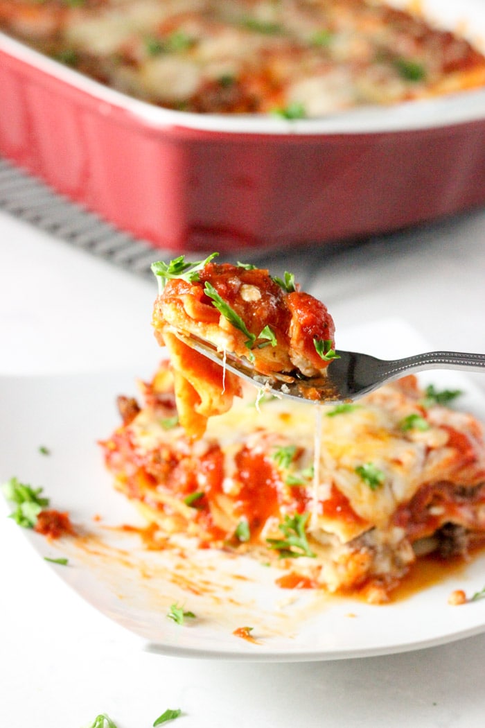 classic lasagna on plate with fork holding bite