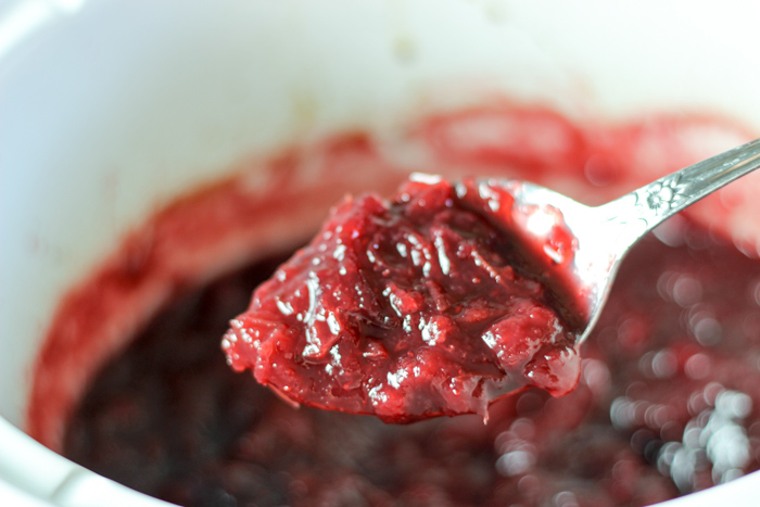spoon with cooked cranberry sauce in crockpot