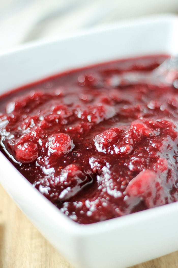 crockpot cranberry sauce in white bowl with spoon