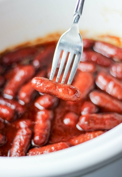 fork holding crockpot little smokies fully cooked in slow cooker