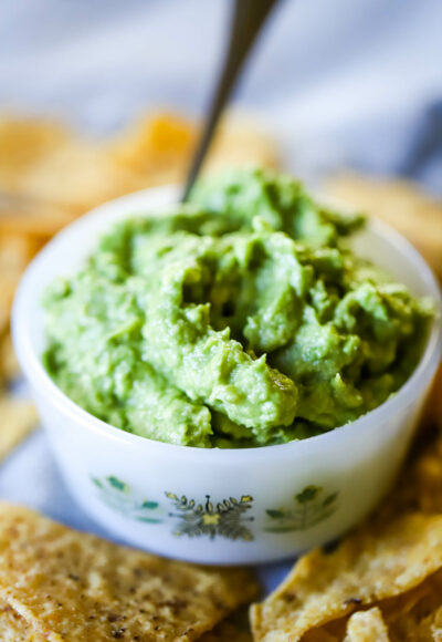 guacamole in a bowl with spoon and surrounded by tortilla chips