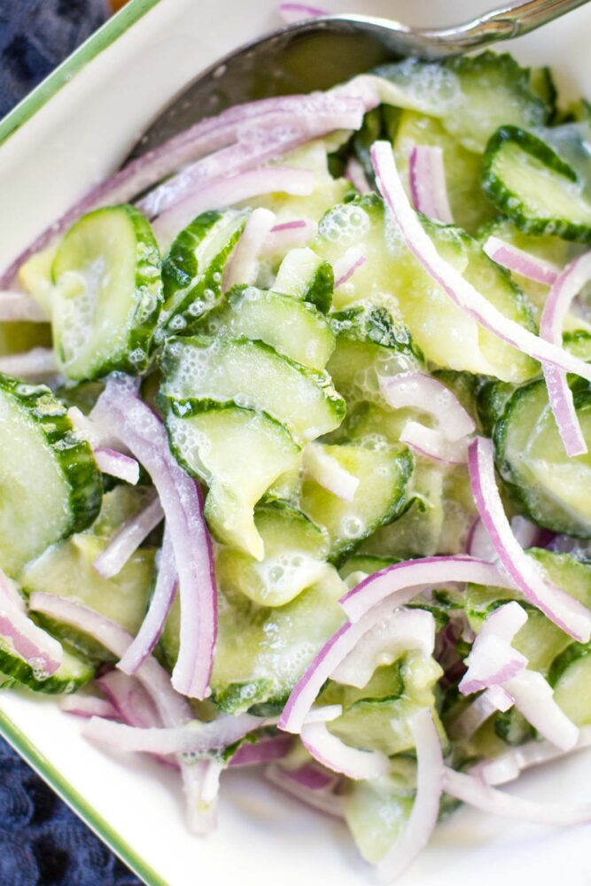 close up of german cucumber salad in bowl with spoon