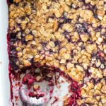 blackberry crumble in baking pan with scoop taken out with spoon