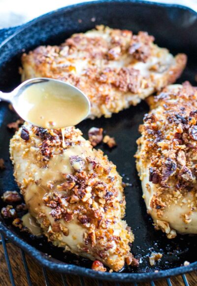 pouring bourbon sauce over baked pecan chicken