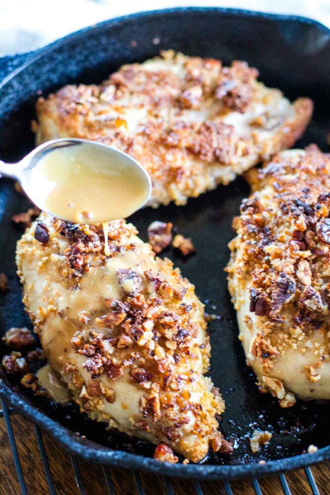 pouring bourbon sauce over baked pecan chicken
