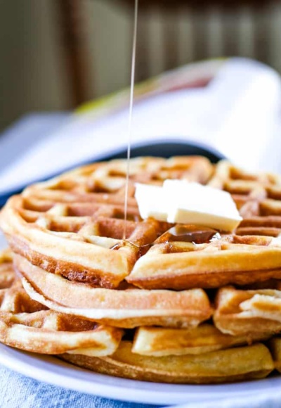 waffle stack on plate with drizzle of syrup and butter