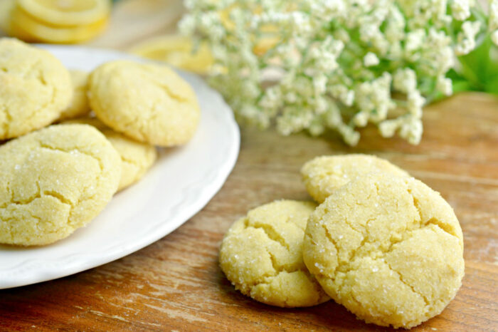 lemon cookies on board with full plate of cookies beside them