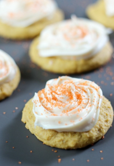 pumpkin cookies with cream cheese icing on dark background