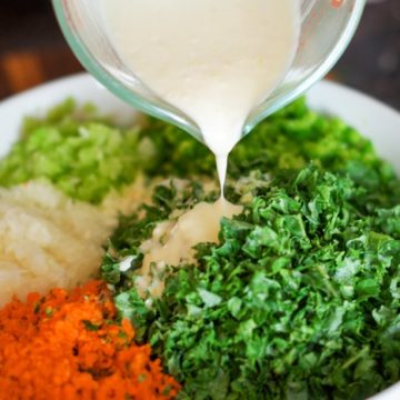 pouring homemade dressing over kale salad ingredients