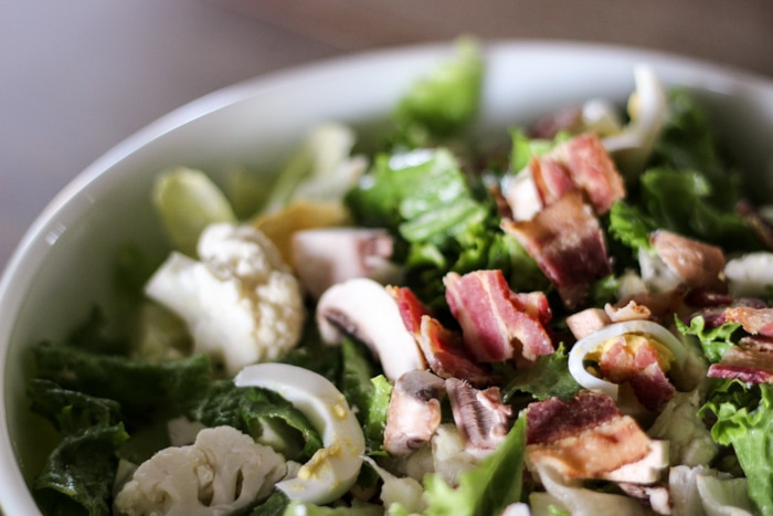 close up of salad with bacon and eggs in bowl