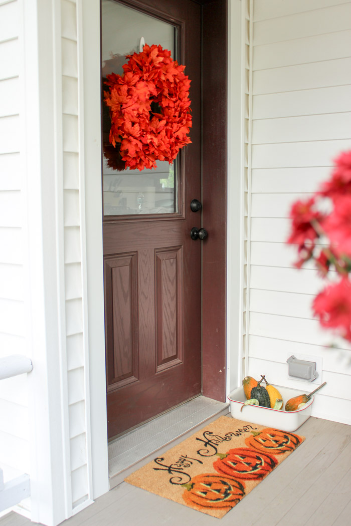 front door with wreath and happy halloween door mat
