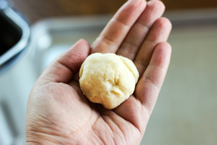 ball of dough in hand after rising