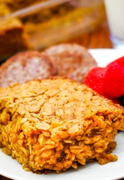 baked oatmeal on white plate with fruit and sausage