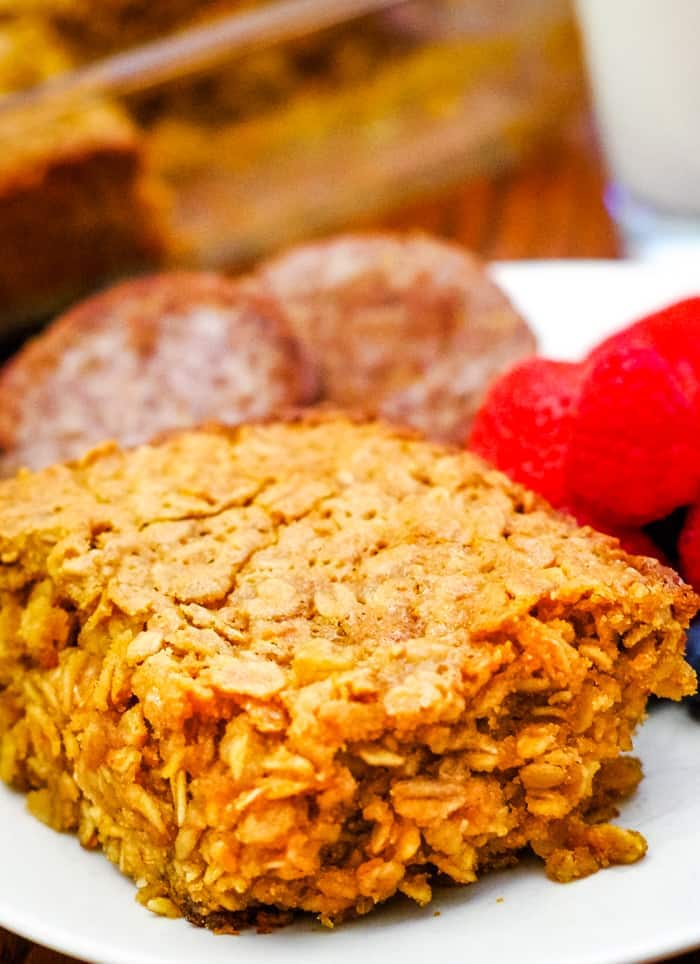 baked oatmeal on white plate with fruit and sausage