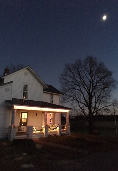 farmhouse at night with moon and Christmas lights