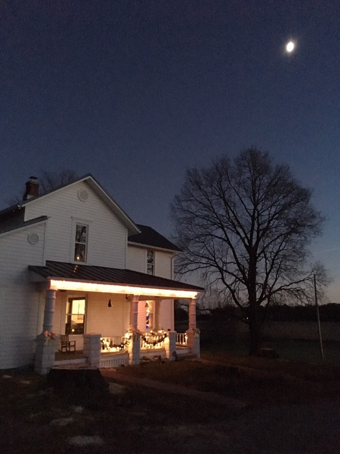 farmhouse at night with moon and Christmas lights