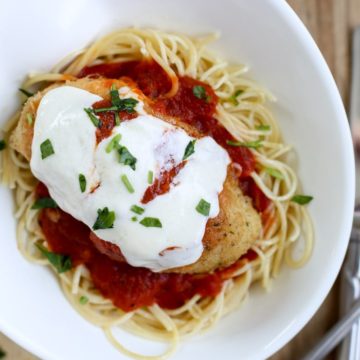 chicken parmesan on pasta on plate with silverware