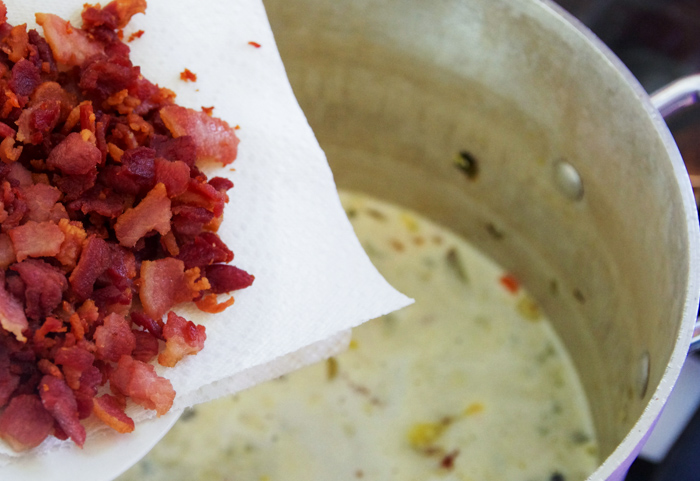 bacon being added to stock pot of potato soup