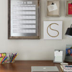 desk with magnetic calendar and frames on wall