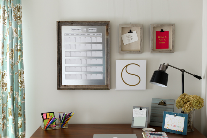 desk with wall art including magnetic calendar and frames