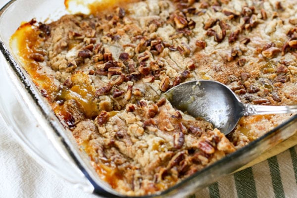 scooping up peach dump cake from dish