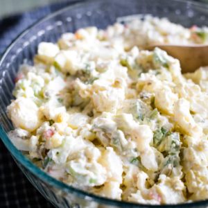 potato salad in bowl with wooden spoon