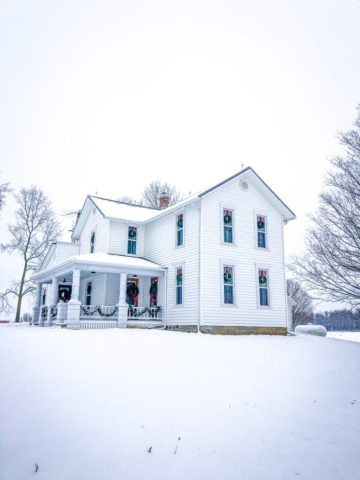 white farmhouse in snow with christmas decorations