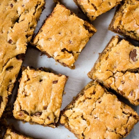 blonde brownie cut in squares on parchment paper