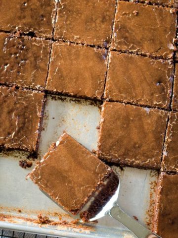 texas brownies in sheet pan with slice on spatula