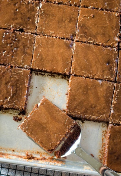 texas brownies in sheet pan with slice on spatula