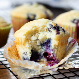 close up of blueberry muffin on cooling rack with bite taken out
