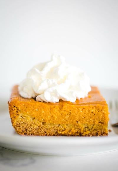 pumpkin gooey butter cake on plate topped with whipped cream