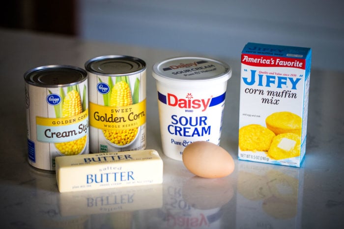 ingredients for corn souffle creamed corn, canned corn, sour cream, egg, jiffy cornbread mix and butter