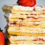 stack of strawberry waffles on plate with strawberry on top