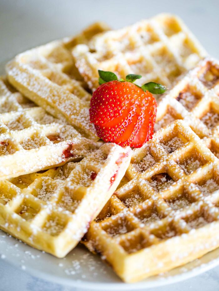 powdered sugar on waffles with strawberry on top