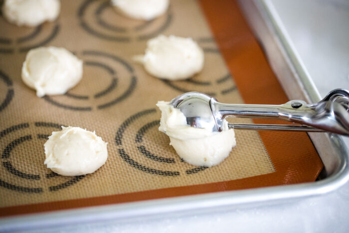 cookie scoop adding dough to baking sheet