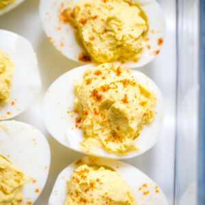 deviled eggs topped with paprika in glass container