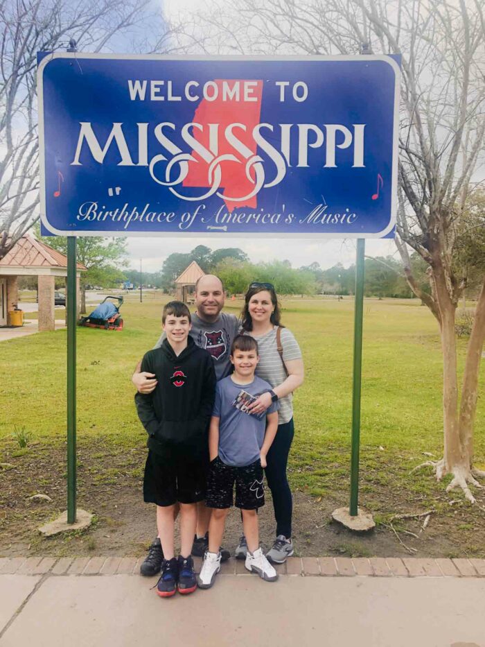 family in front of Mississippi state sign