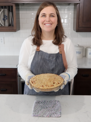 Lynette Rice standing in kitchen holding apple pie