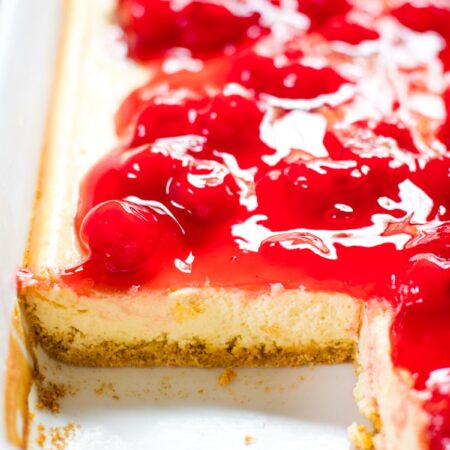 view of cherry cheesecake in pan with slice taken out