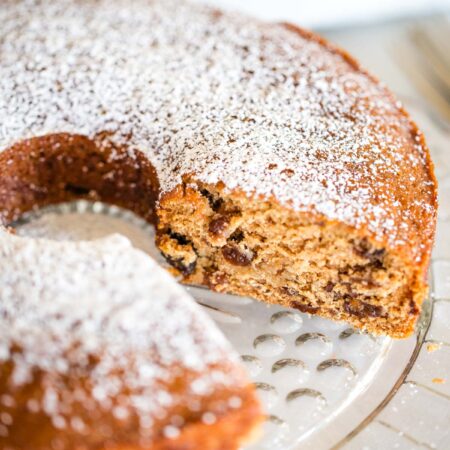 raisin cake on serving plate dusted with powdered sugar