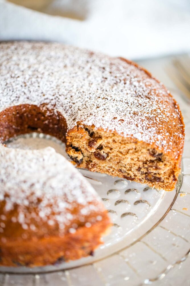 raisin cake on serving plate dusted with powdered sugar