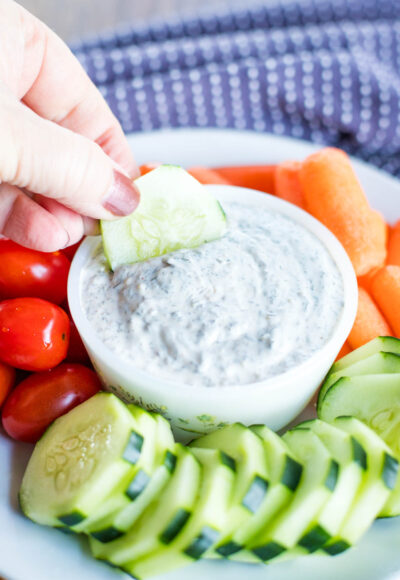 veggie dip surrounded by veggies and dipped by cucumber