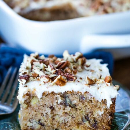hummingbird cake slice on plate with fork with baking pan behind
