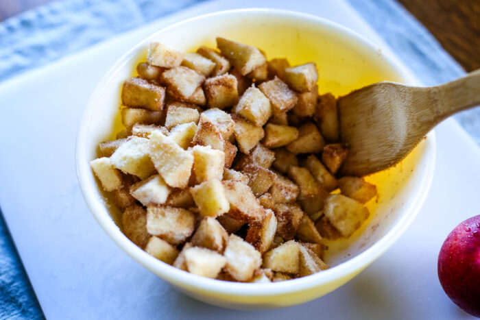 homemade dutch apple pie filling in bowl stirred with wooden spoon