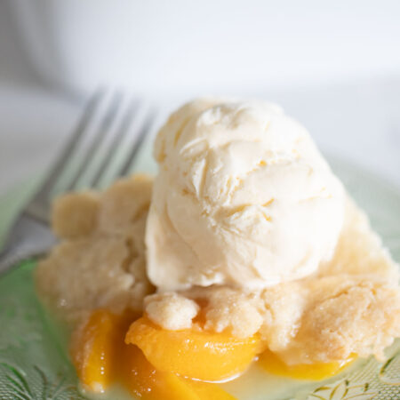 peach cobbler on plate topped with ice cream