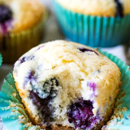 blueberry muffins on table with bite taken out of one muffin
