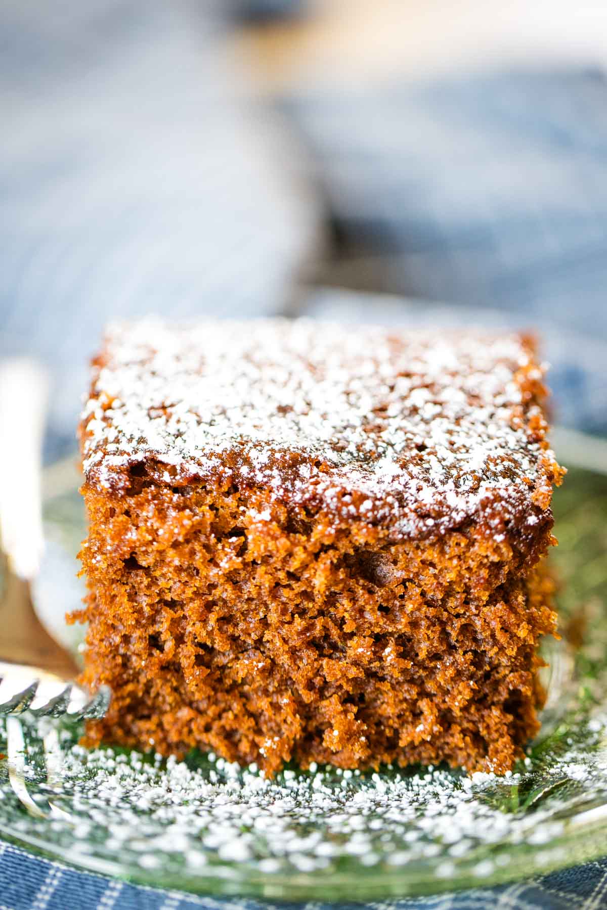 slice of gingerbread on plate with fork and topped with powdered sugar